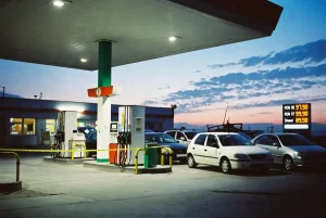 Petrol station forecourt at dusk with pumps cordoned off with yellow tape and cars queuing, illustrating the 2026 global fuel crisis