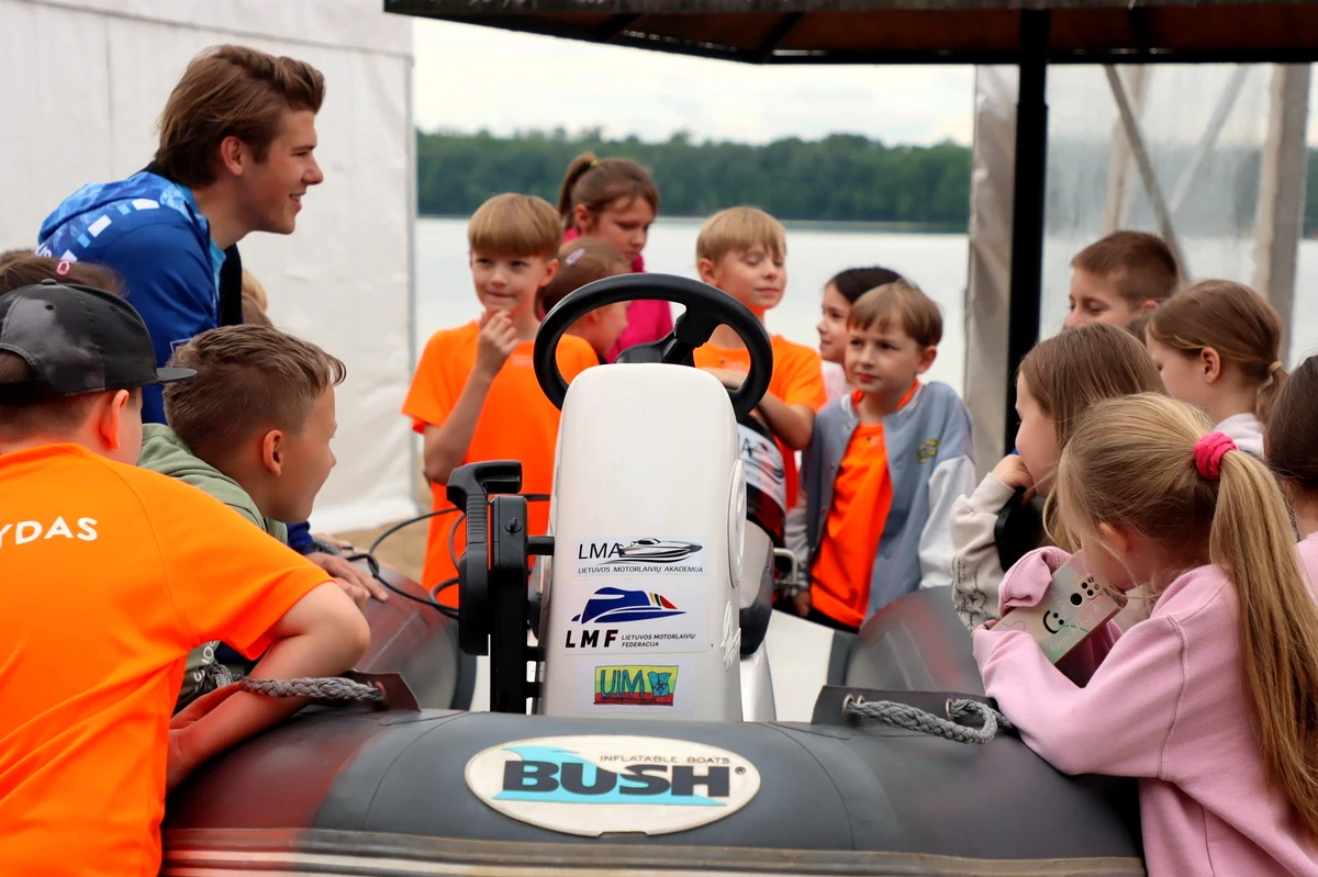 Children gather around an LMA boat during a briefing session at the Lithuanian Motorboat Academy, Kaunas