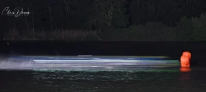 Night racing on the River Seine at Poses — a powerboat leaves light trails across the dark water during the 24 Heures Motonautiques de Normandie 2026. Photo: Chris Davies / Powerboatpix.com