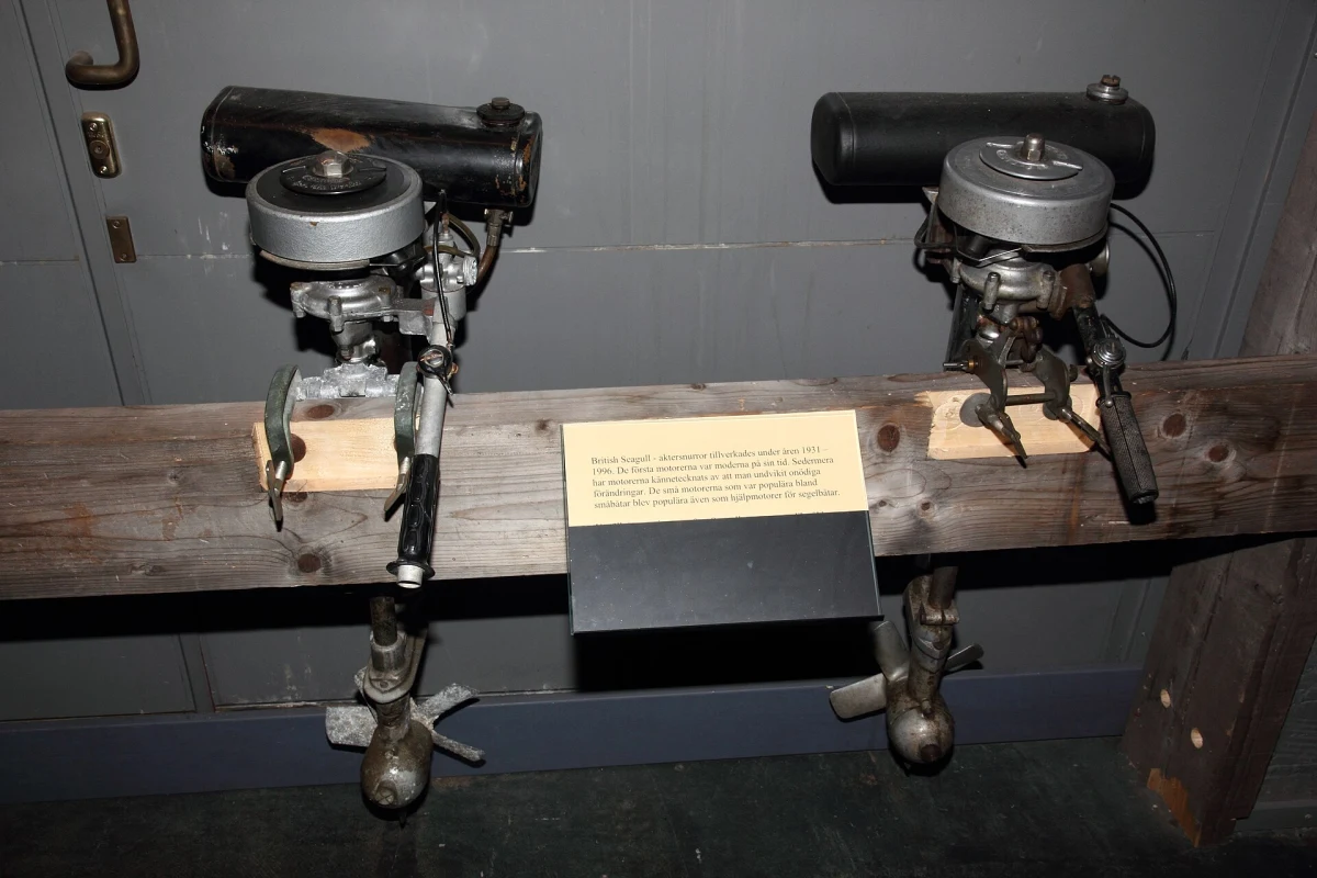 Two vintage British Seagull outboard motors mounted on a wooden beam in a maritime museum display