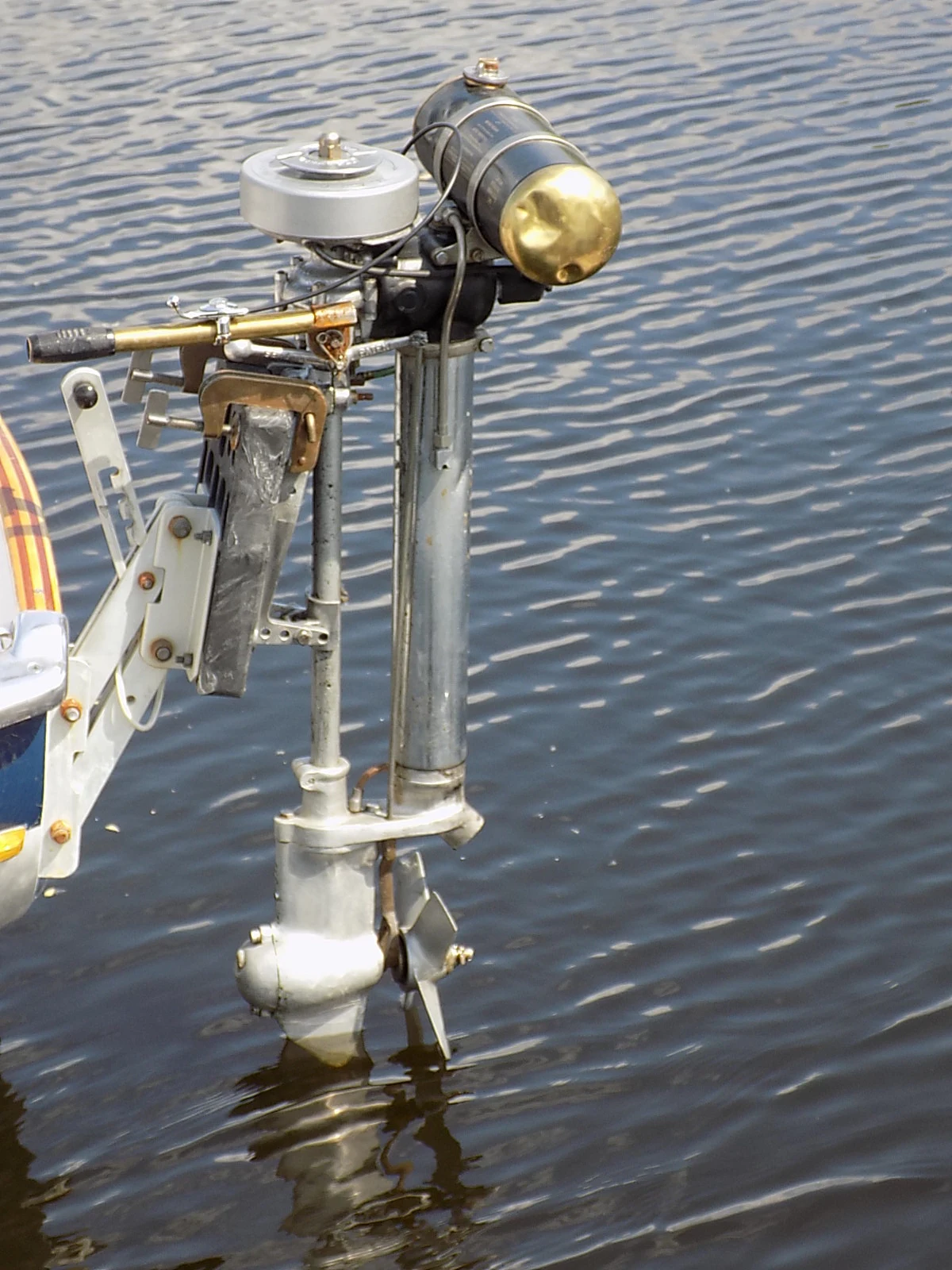A British Seagull outboard motor mounted on a small boat transom, tilted into the water