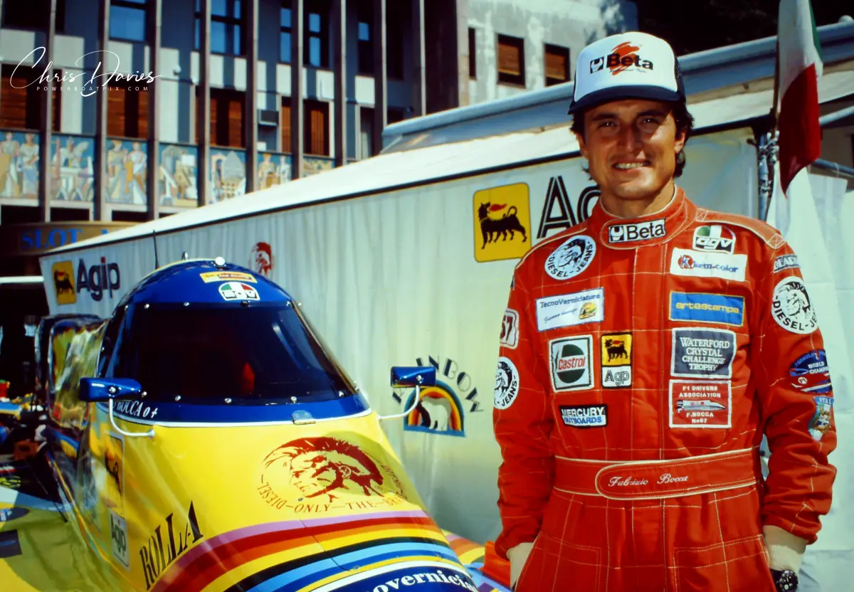 Fabrizio Bocca in Rainbow Team race suit beside his Formula 1 boat at Campione d'Italia, 1993, with the Rainbow Team polar bear logo visible on the cockpit