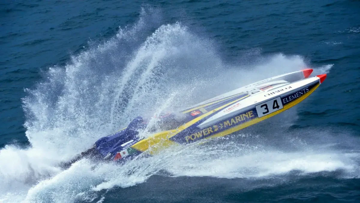 An offshore powerboat racing at speed, throwing spray