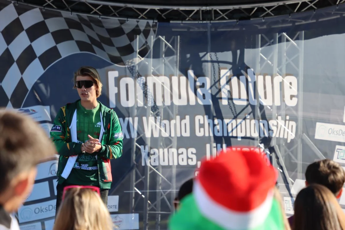 A speaker addresses pilots in front of the Formula Future XV World Championship Kaunas banner