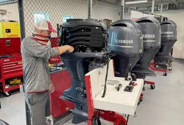 A technician working on modern Yamaha outboard motors in a dealer workshop