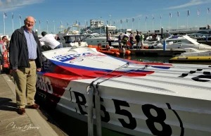 Don Shead standing beside Cinzano, race number 558, the Class 1 boat he designed, at Cowes in 2010