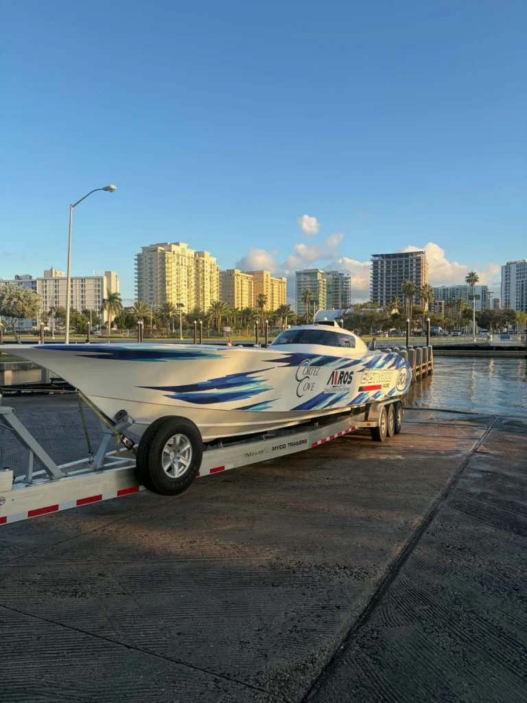 Go GPS Racing's white and blue Fountain Super Vee on a MYCO trailer at a boat ramp, with Cortez Cove, Airos and Eastwood Racing sponsor livery