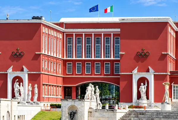 CONI headquarters at the Foro Italico in Rome, a red building with Olympic rings, marble statues and the Italian and European flags