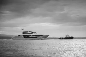 Sunseeker 134 Superyacht under tow along the Dorset coast, with a tug ahead and a helicopter overhead