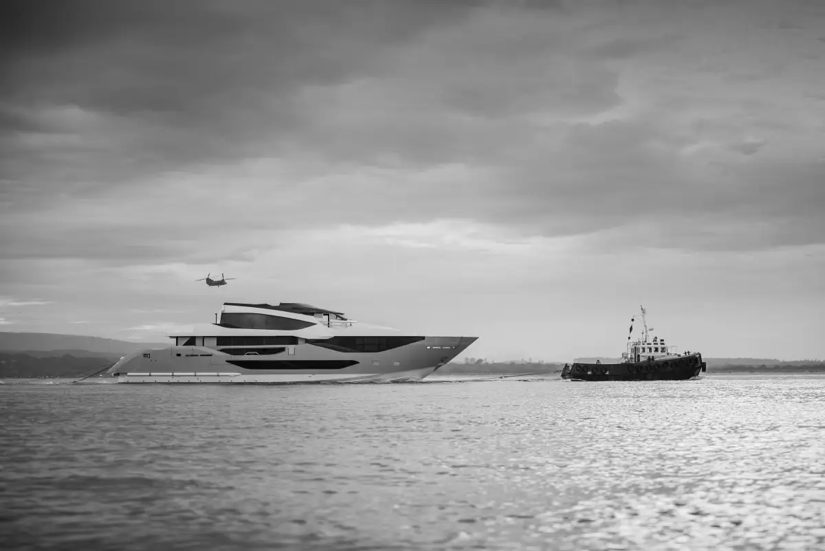 Sunseeker 134 Superyacht under tow along the Dorset coast, with a tug ahead and a helicopter overhead