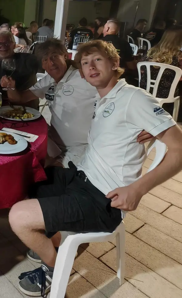 Caleb Jelf in a white team polo shirt, seated at an evening event table