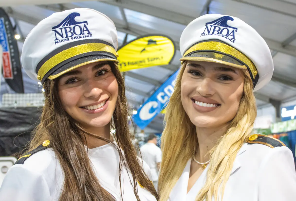 Two NBOA Marine Insurance hostesses in captain's hats at the Fort Lauderdale International Boat Show