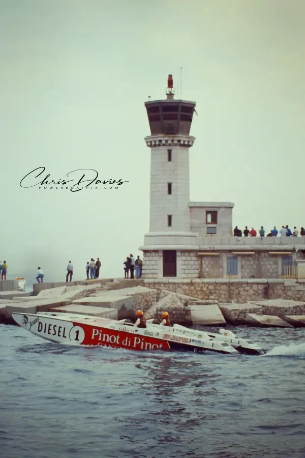 Pinot di Pinot running past the lighthouse at the Monaco harbour entrance, with spectators on the harbour wall, October 1990